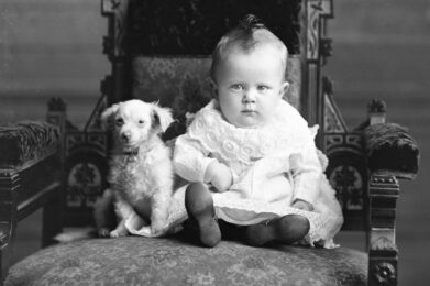 A baby and a dog posing on a chair.